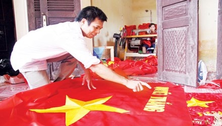 Anh Phục đang kiểm tra lá cờ sau khi hoàn thiện.