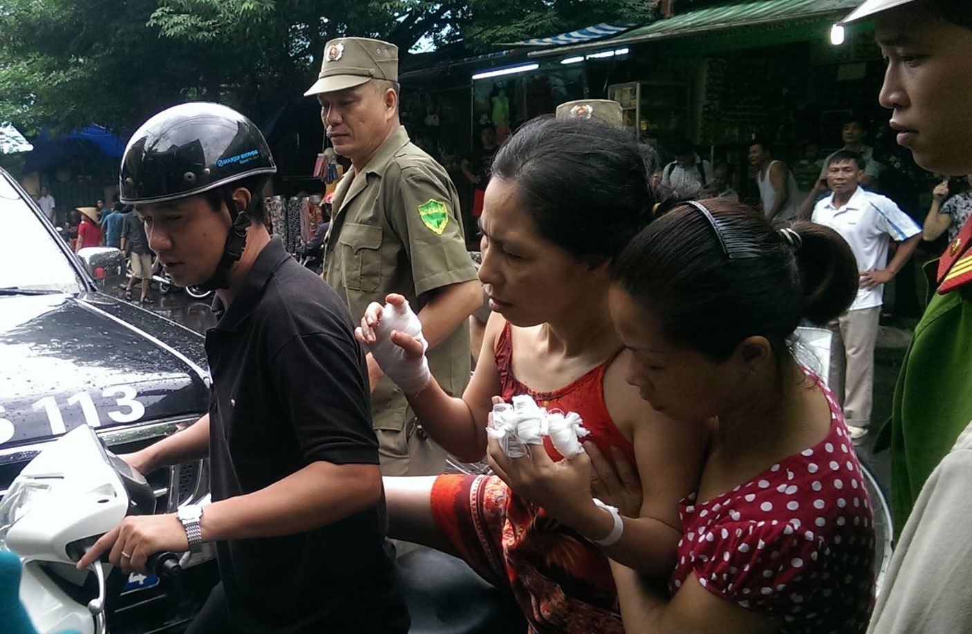 Người phụ nữ bị chém được cảnh sát đưa ra khỏi hiện trường.