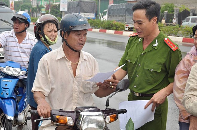 Công an phát tờ rơi cho người dân. Ảnh: Ngọc An.