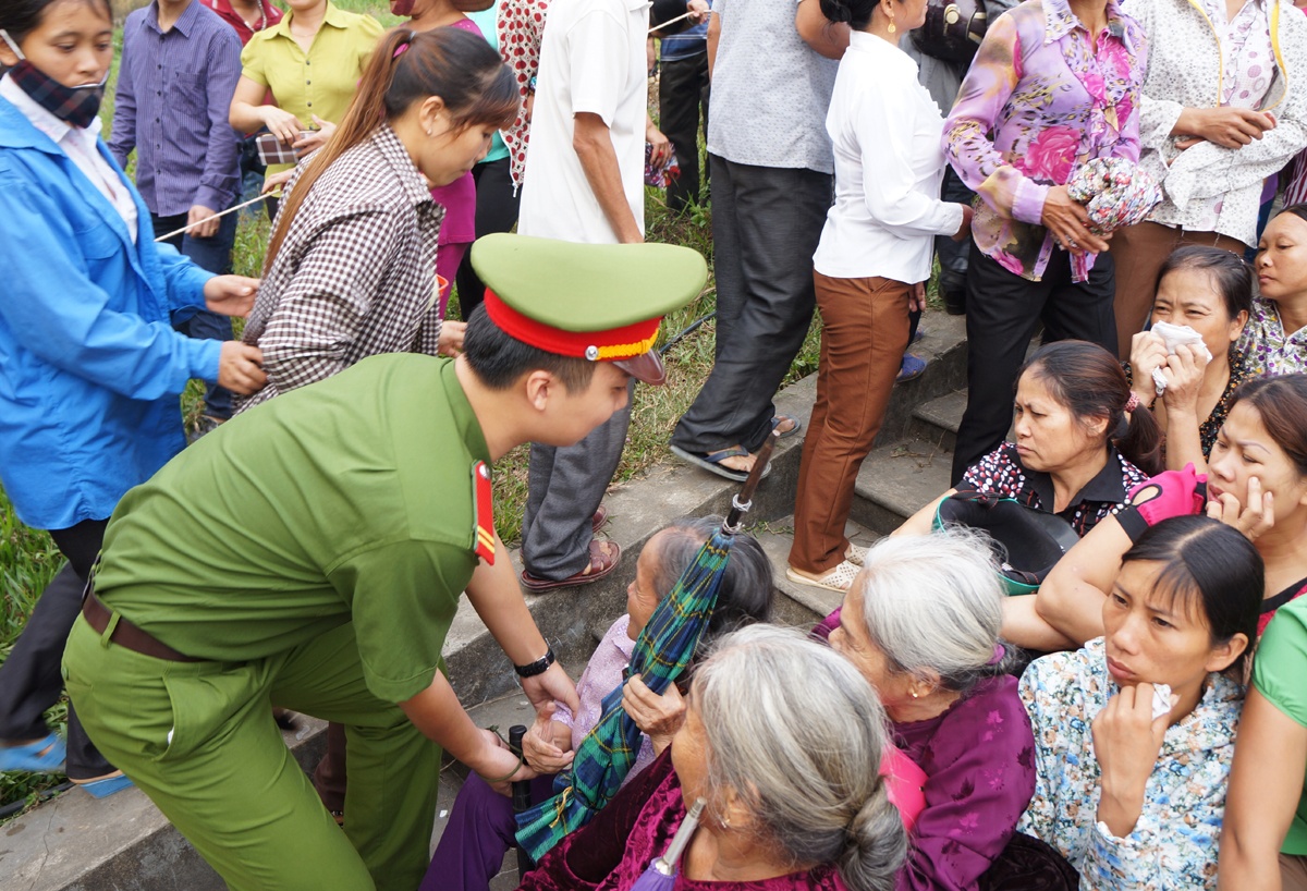 Số lượng người đến xem vượt quá sức chứa của khu vực xét xử. Người dân rất khó khăn trong việc tìm chỗ ngồi dự xem xét xử. Trong ảnh, một cụ bà ngồi vào lối đi được lực lượng công an nhắc nhở di chuyển.