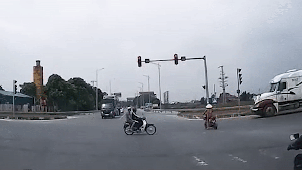 Nguoi phu nu di xe dap dien suyt bi container tong khi vuot den do hinh anh