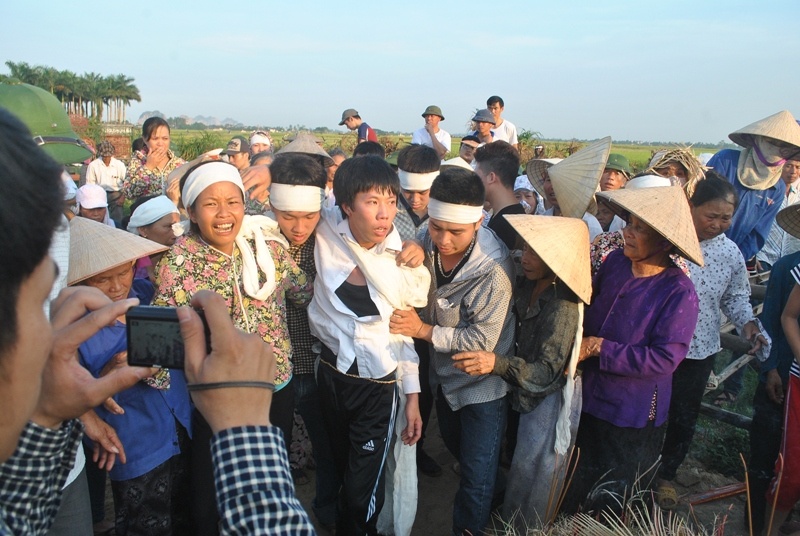 Anh Lê Sĩ Long (áo trắng, giữa) thẩn thờ trước cái chết đột ngột của cha mẹ.