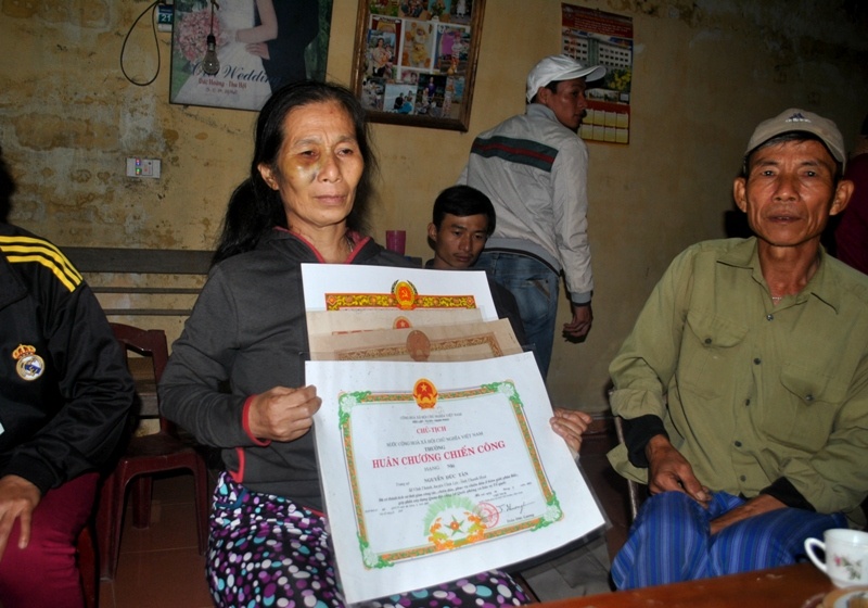 Bà Tân cầm trên tay những bằng khen do nhà nước trao tặng cho chồng.
