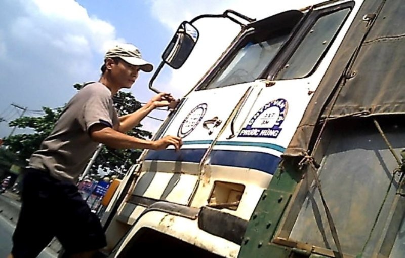 Một người nghiện đu xe tải để xin tiền - Ảnh: H.Lộc