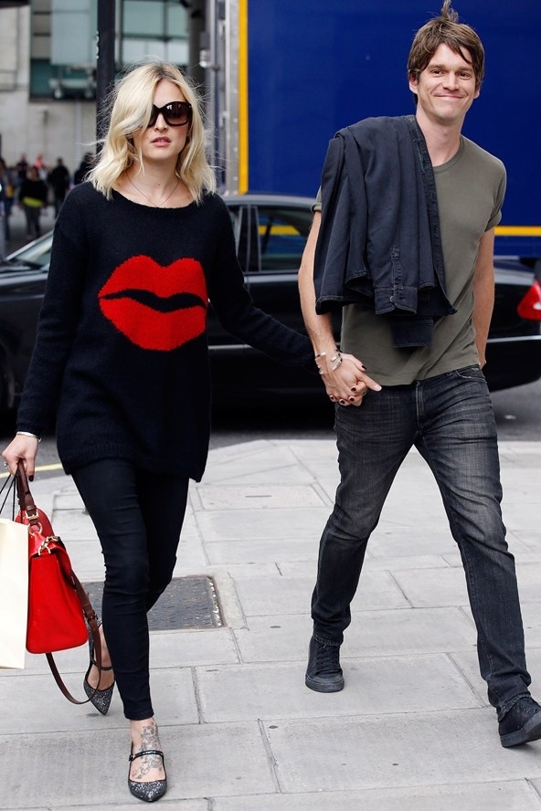 Vợ chồng nhà Wood tươi tắn ở London khi Jesse Wood khỏe khoắn cùng áo phông quần bò thì cô nàng Fearne Cotton đơn giản mà nổi bật với sweater in hình đôi môi đỏ thắm tiệp màu cùng túi xác.