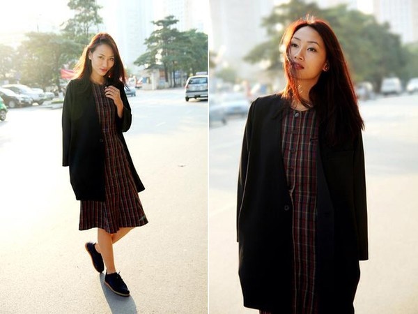 Áo khoác dáng dài đen phối cùng váy midi dáng suông họa tiết caro tối màu và giày bệt tạo cho Trang Khiếu style lạ mắt.