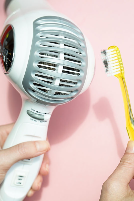 Bụi và lông kẹt vào cánh quạt của máy sấy tóc sẽ khiến máy hoạt động yếu đi. Hãy dùng bàn chải đánh răng để lấy chúng ra nhanh hơn.