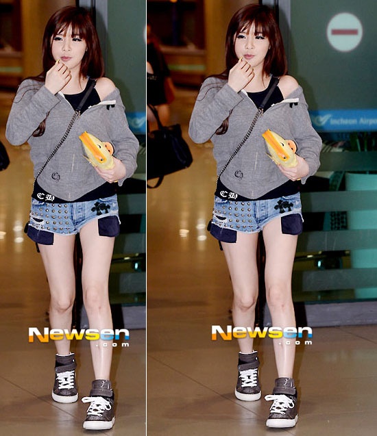 Park Bom gợi cảm với quần short đinh tán, giày sneaker và khoác áo  trễ một bên vai..