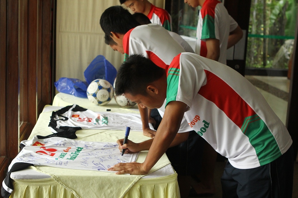 Trong lúc chờ đợi bầu Đức, các cầu thủ U19 Việt Nam tranh thủ ký áo đấu...