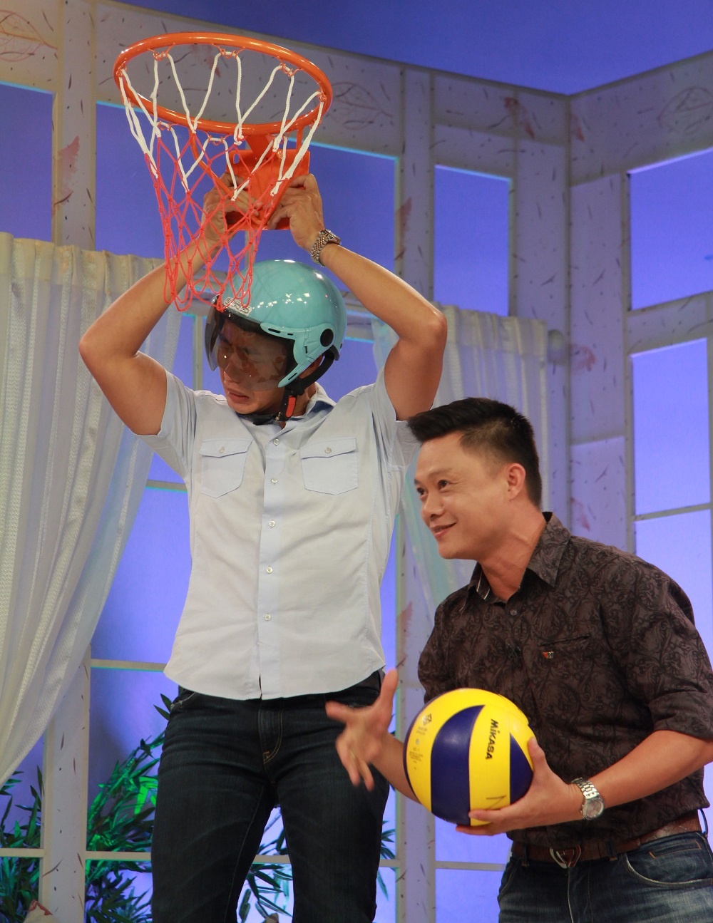 Hai cô được yêu cầu dùng quả bóng chuyền ném vào rổ do BTV Thanh Tùng cầm. 