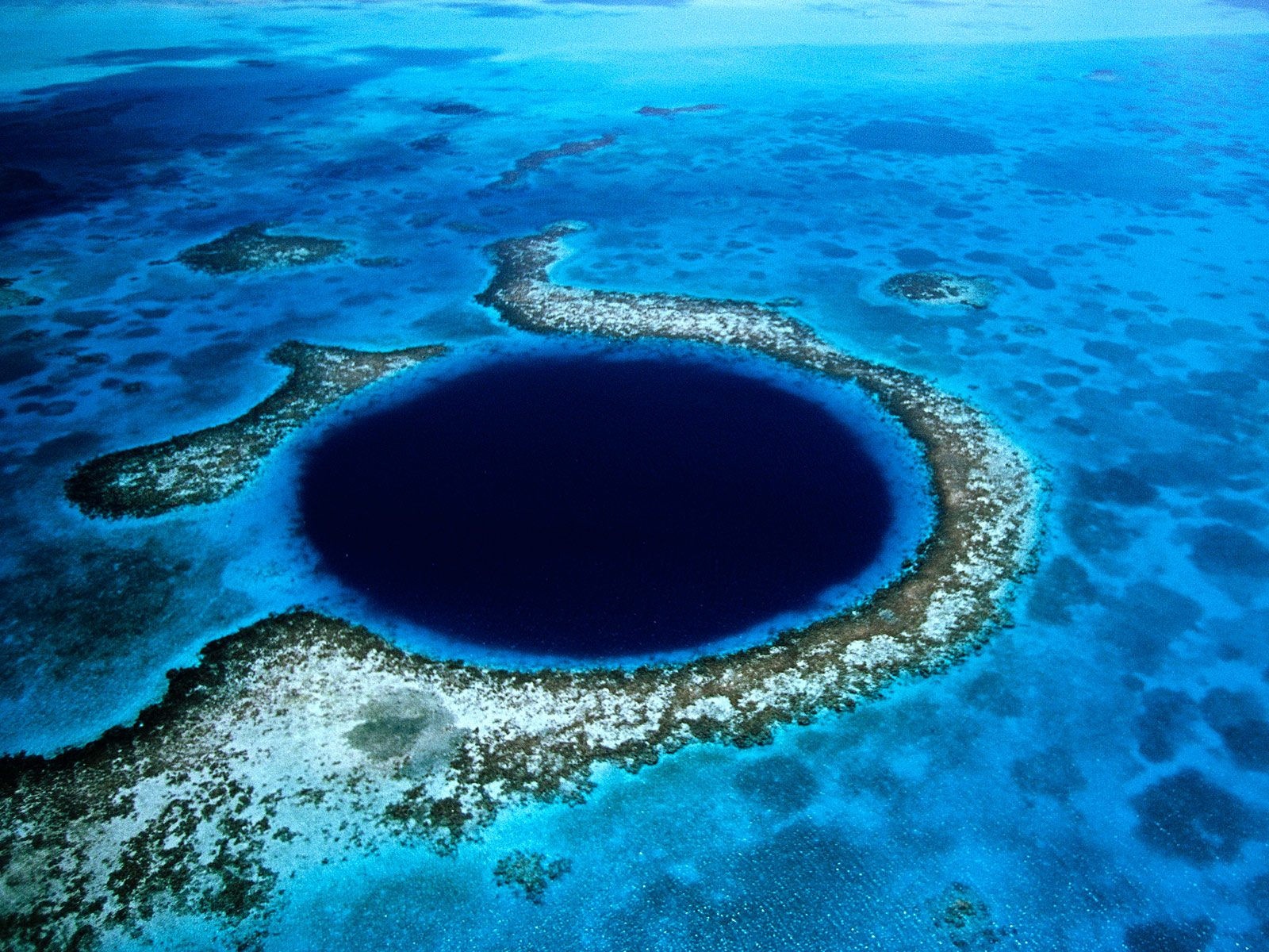 5. Great Blue Hole, Belize   The Great Blue Hole là một hố ngầm ngoài khơi trên bờ biển Belize. The Great Blue Hole có hình tròn với độ rộng này rộng 305 mét, sâu khoảng 126 mét. Nhìn từ trên cao, trông nó giống như con mắt khổng lồ xanh thẫm vô cùng quyến rũ và kì bí. Các nhà khoa học đã phân tích nhũ đá của The Great Blue Hole và cho rằng nó đã bắt đầu được hình thành từ hơn 15.000 năm trước. The Great Blue Hole được coi là một trong những kỳ quan địa chất đẹp nhất của thế giới.