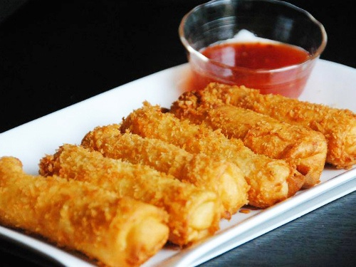 Trứng gà đập ra chén, đánh tan. Nhúng từng cuốn chả giò vào trứng gà sau đó lăn đều qua một lớp bột chiên xù. Cho dầu vào chảo, dầu nóng cho chả giò vào chiên vàng đều, vớt ra thấm ráo dầu. Nước chấm: Cho đường lên chảo nấu tan chảy, thêm nước mắm vào hòa tan, tắt bếp, trút ra chén. Thêm xốt ớt, tỏi, ớt băm vào trộn đều.