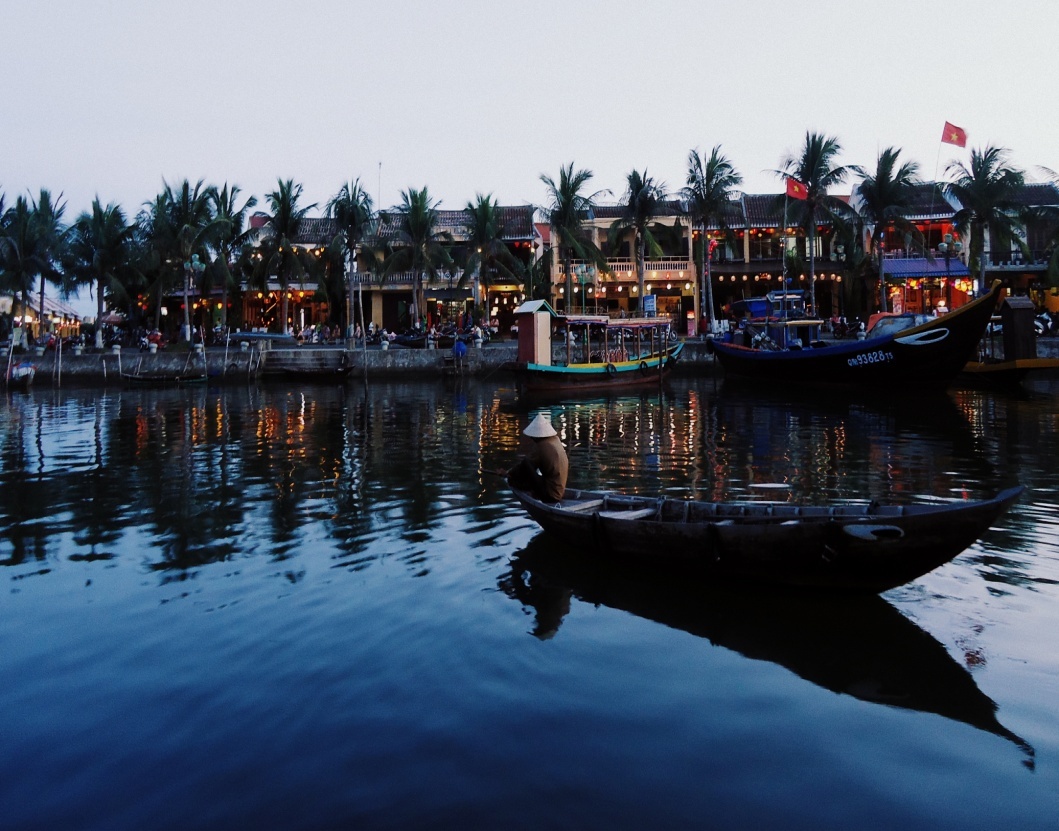 Bóng xế. Dáng ngồi cô độc của người lái đò trên Hoài, đối lập với đèn lồng rực rỡ bên kia sông.