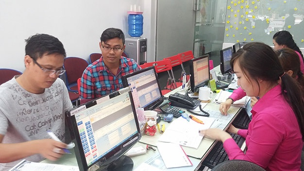 Khách Trịnh Lê Viễn Kha (bìa trái) làm thủ tục mua tour đi Thái Lan khởi hành ngày 22-2 - Ảnh: Lê Nam