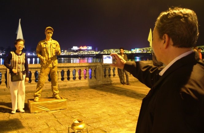 Chụp hình bên tượng người ở phố đi bộ Huế - Ảnh: PHAN THÀNH.