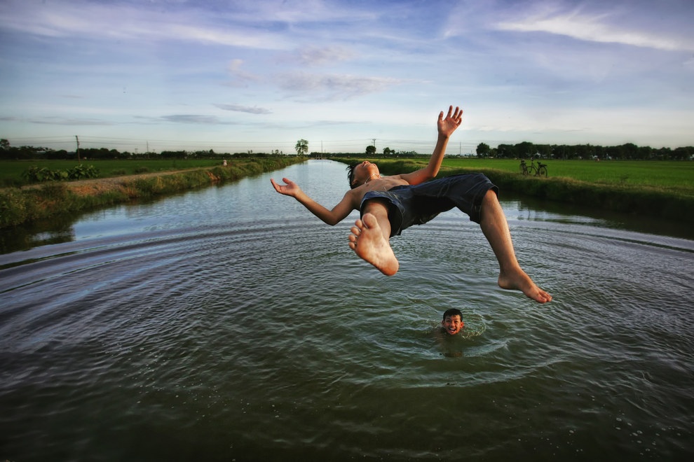 2. Cậu bé nhảy lộn vòng xuống dòng sông tắm gần làng Nghiêm Xuyên, Hà Nội, Việt Nam. Ảnh: Trần Việt Phương.