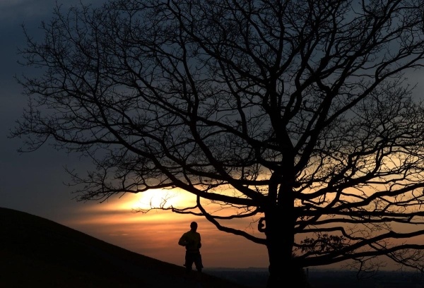 Người đàn ông chạy bộ trong hoàng hôn sau một ngày xuân ấm áp tại công viên Olypmpic, Munich, miền nam nước Đức.