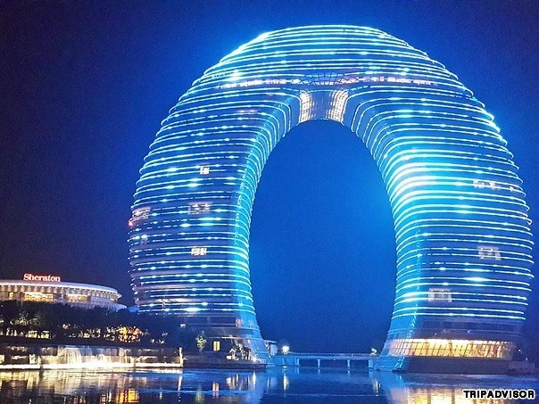 3. Sheraton Huzhou Hot Spring, Huzhou, Trung Quốc. Nổi tiếng với thiết kế hình chiếc bánh donut, khu nghỉ dưỡng Sheraton Huzhou Hot Spring, Trung Quốc sở hữu những tiện ích và dịch vụ vô cùng khác lạ, đặc biệt. Ví như cầu dưới nước làm đường nối giữa hai tòa tháp. Ban đêm, đèn sẽ chiếu sáng toàn bộ tòa nhà, sáng rực rỡ lung linh.