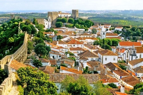 Óbidos (Bồ Đào nha) Thị trấn Óbidos nằm trên một ngọn đồi và được bao quanh bởi một bức tường kiên cố. Trong thế kỷ thứ 8 người Moor đã thành lập một pháo đài trên đỉnh đồi. Sau đó nó bị chiếm bởi vị vua đầu tiên của Bồ Đào Nha, Afonso Henriques vào năm 1148. Lâu đài Óbidos và các bức tường đã được xây lại trong thế kỷ 14. Các bức tường được làm bằng đá vôi và đá cẩm thạch. Thị trấn cũng được mở rộng trong khoảng thời gian này, những khu định cư mới được tạo ra bên ngoài các bức tường của thị trấn. Những đường phố, quảng trường, tường và lâu đài khổng lồ được bảo tồn tốt kể từ thời trung cổ đã biến ngôi làng đẹp như tranh vẽ này trở thành một điểm thu hút du lịch nổi tiếng ở Bồ Đào Nha. Điểm đến này hấp dẫn du khách bằng những ngôi nhà tường trắng với những con đường lát đá cuội cùng những nhà hàng ven đường phục vụ món Salad bạch tuộc và thức uống truyền thống Bồ Đào Nha tên ginjinha.
