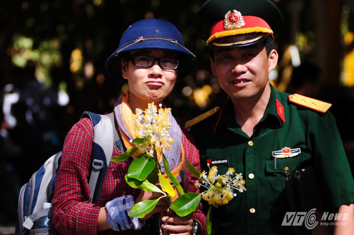 Nữ cán bộ đoàn công tác chụp ảnh cùng sỹ quan quân đội bên cành hoa mù u trắng được các chiến sỹ tặng làm kỷ niệm (Tùng Đinh/Thực hiện).