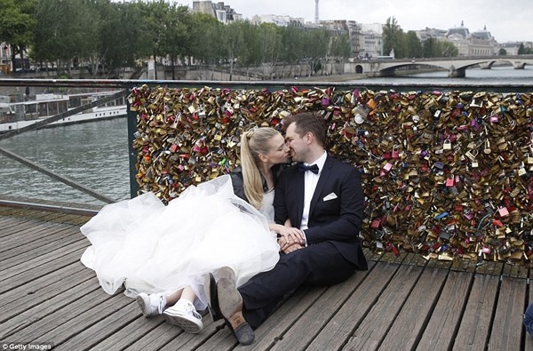 Cây cầu nổi tiếng Ponts des Arts nằm ở vị trí giữa Vườn Tuileries và Bảo tàng D’Orsay. Bắt đầu từ năm 2008, dân Paris và du khách tới thành phố thường tới cây cầu đi bộ để thể hiện tình yêu bằng những chiếc khóa xinh xắn. Họ treo ổ khóa ở thành cầu và ném chìa khóa xuống sông Seine. Hành động này được coi là để khẳng định tình yêu của họ luôn bền chặt. Trong ảnh là một đôi tình nhân chụp ảnh cưới đúng ngày 1/6 bên mảng lan can cầu vừa bị dỡ.
