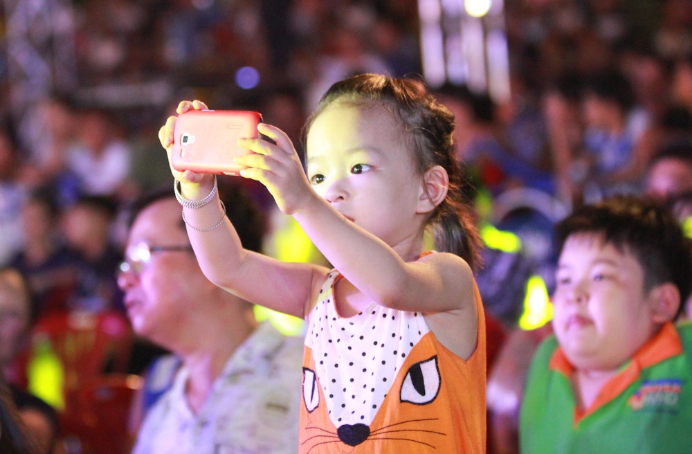 Một em nhỏ chăm chú chụp hình các tiết mục lễ hội đường phố.