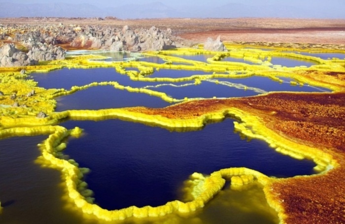 Dallol, Ethiopia. Khu vực ngay gần núi lửa đã ngừng hoạt động trong thời gian qua và là nơi sở hữu nhiệt độ khủng khiếp với mức trung bình hơn 41 độ C trong suốt gần 100 năm qua. Ngoài ra, Màu sắc tươi sáng và rực rỡ xuất hiện xung quanh khu vực miệng núi lửa như màu trắng, vàng, đất son, xanh lá cây và đỏ là do có sự kết hợp của những con suối nước nóng, núi lưu huỳnh, hồ axit, hồ oxit sắt, lớp muối ẩn. Không ngạc nhiên khi gần như không có người ở tại đây.