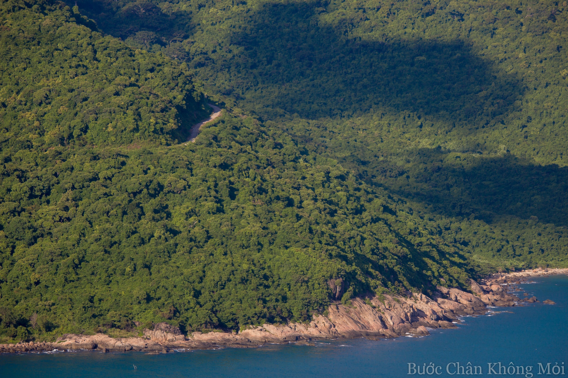 Biển xanh ôm núi, núi ôm con đường bé nhỏ uốn cong xuyên qua những tán lá cây um tùm, xanh mướt.