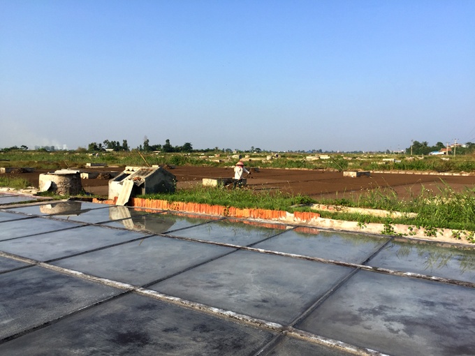 Nước chạt nồng độ cao được rải trên mặt sân ximăng, nhờ nắng bốc hơi nước và dần kết tinh thành muối. Ảnh: Băng Giang.