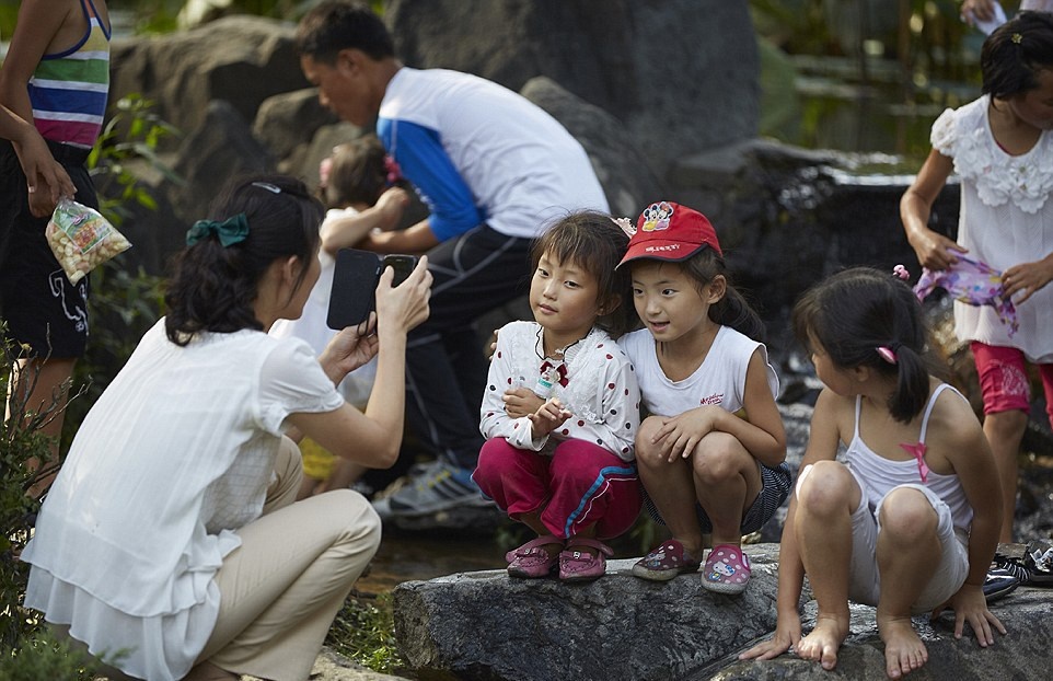 Một người mẹ chụp ảnh cho con gái mình bằng một điện thoại thông minh. Người dân Triều Tiên đã bắt đầu chú ý tới điện thoại của họ.