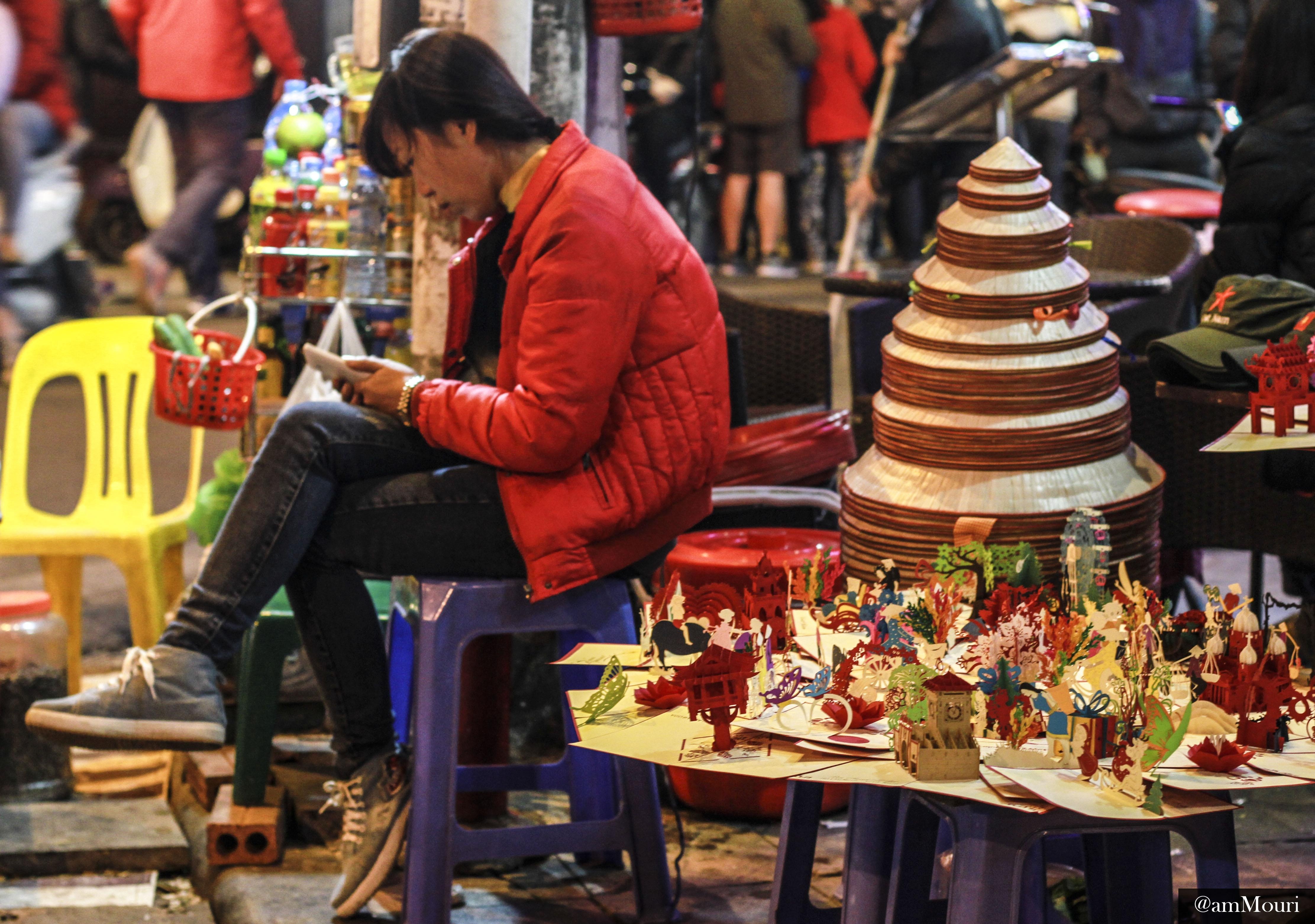 Trong khi nhiều người mải mê với ca nhạc thì chị bán hàng này tranh thủ thời gian đọc tin tức.