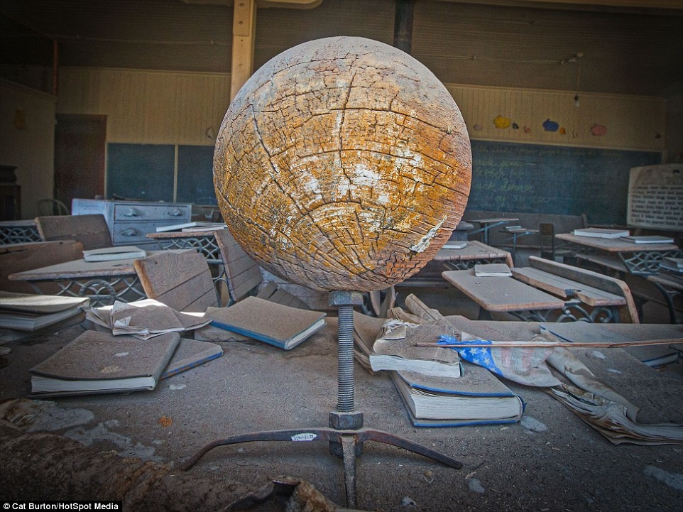 Sách vở, bàn ghế dày bụi và quả địa cầu nứt nẻ.