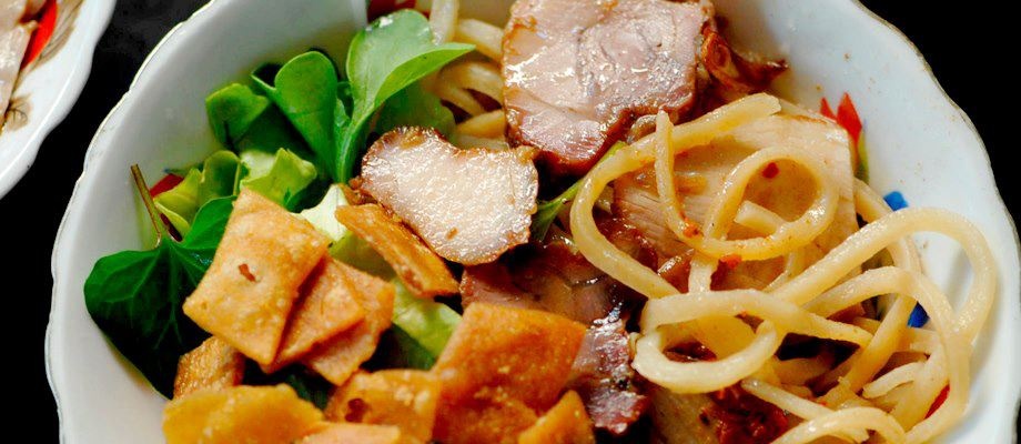 Cao lầu: Là món ăn nổi tiếng số một của phố cổ. Người dân nơi đây truyền tai nhau rằng cái đặc biệt là ở cách làm sợi mì cao lầu, rằng gạo phải được ngâm bằng nước tro đốt bằng củi lấy từ Cù Lao Chàm, nước phải lấy từ giếng Bá Lễ duy nhất ở Hội An, rằng sợi mì phải được hấp nhiều lần mới có được màu vàng nhẹ cùng vị dai dai đậm đà như vậy. Mì cao lầu trộn cùng những cọng giá trắng ngần, những lát thịt xá xíu và thịt heo luộc mềm mại, rắc lên lớp đậu phộng rang cùng các loại rau bạc hà, húng quế thơm nồng. Cao lầu bán ở các hàng gánh lề đường đến các nhà hàng trên đường Trần Phú, nổi tiếng nhất là quán Bà Bé. (Ảnh: Hoian Heritage)