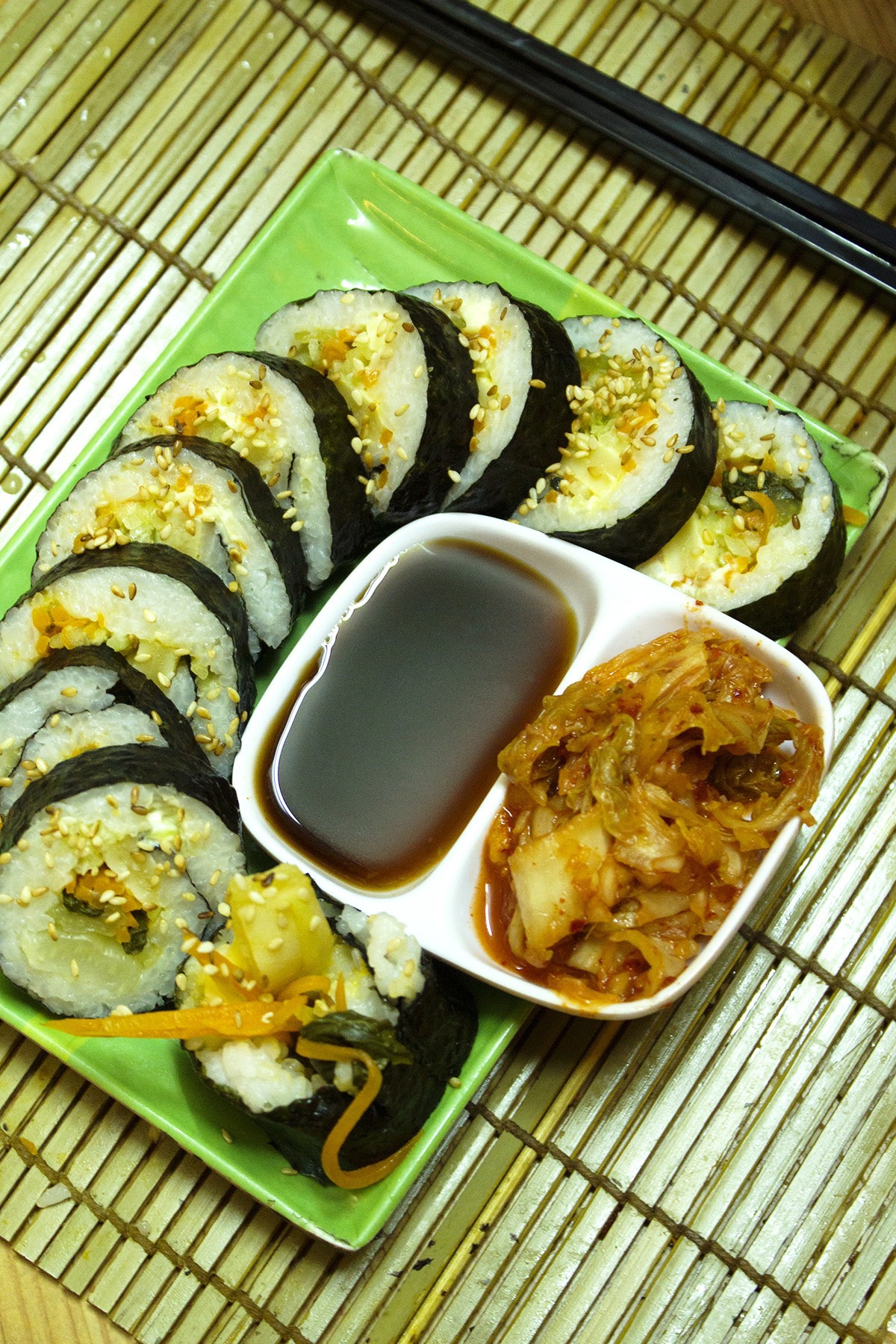 Dọn kimbap ra đĩa, rắc ít dầu mè lên trên, dọn ăn kèm kim chi và nước tương. Món ăn do quán Kim bắp (hẻm 337 Lê Văn Sỹ, quận Tân Bình, TP HCM) hướng dẫn.