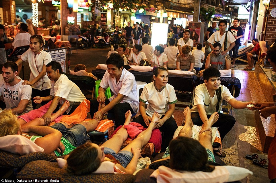 Du khách thư giãn với dịch vụ massage chân bên đường phố.