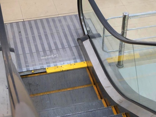 Be trai bi ket tay vao thang cuon khi nguoi lon mai dung dien thoai hinh anh