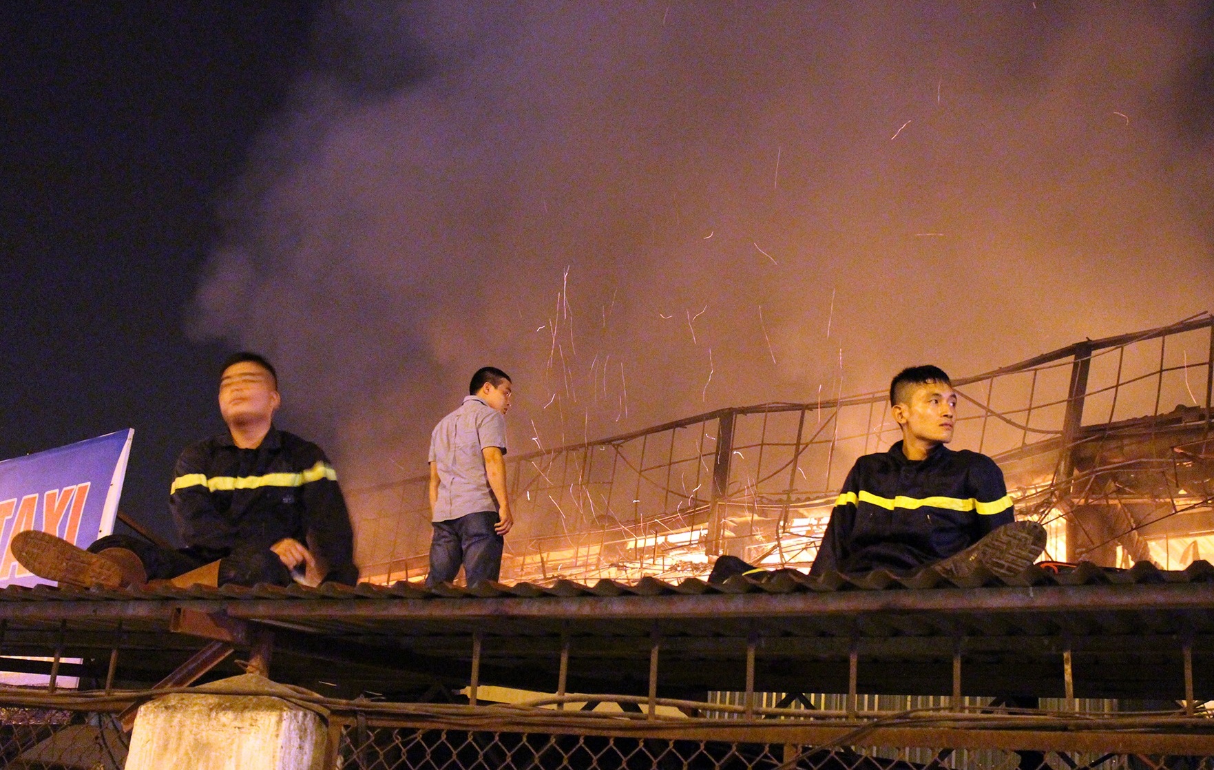 Lính cứu hỏa ngồi nghỉ giải lao sau nhiều giờ ứng cứu nhưng chưa thể dập được ngọn lửa.  Ảnh: Mạnh Thắng.