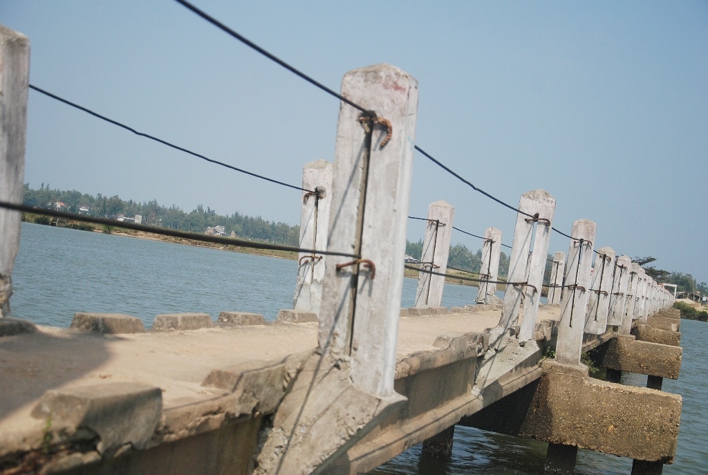 chiều ngang của cây cầu chỉ là 0,8 m, đủ cho hai người đi bộ tránh nhau. Dù có biển cấm xe máy, người dân 2 xã Tam Tiến và Tam Xuân 2 vẫn hàng ngày phóng xe qua lại.