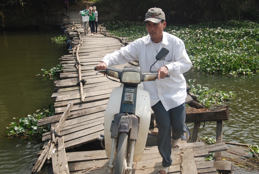 Nguyễn Văn Thăng khi ông từ nhà ở tổ 2 qua cầu sang thị trấn Nam Phước chuẩn bị đất làm vụ đông xuân. Ông Thăng cho biết gia đình có 8 sào gồm 4 sào ruộng và 4 sào màu. Vì nhà và đất ruộng cách con sông Bà Rén nên mỗi mùa thu hoạch không còn cách nào khác là phải chở lúa về buộc đi qua cây cầu này.  Ông Thăng nói: “Dân tổ 2 chúng tôi đều làm nông nghiệp với hơn 30ha, trong khi đất sản xuất nằm hết ở bên kia sông nên phải phụ thuộc vào cây cầu này. Nếu không có cầu, muốn đi làm đồng chỉ còn cách chạy xe máy xuống QL1A rồi quay ngược trở ra rồi rẻ lên thị trấn Nam Phước mất khoảng gần 10 cây số”.