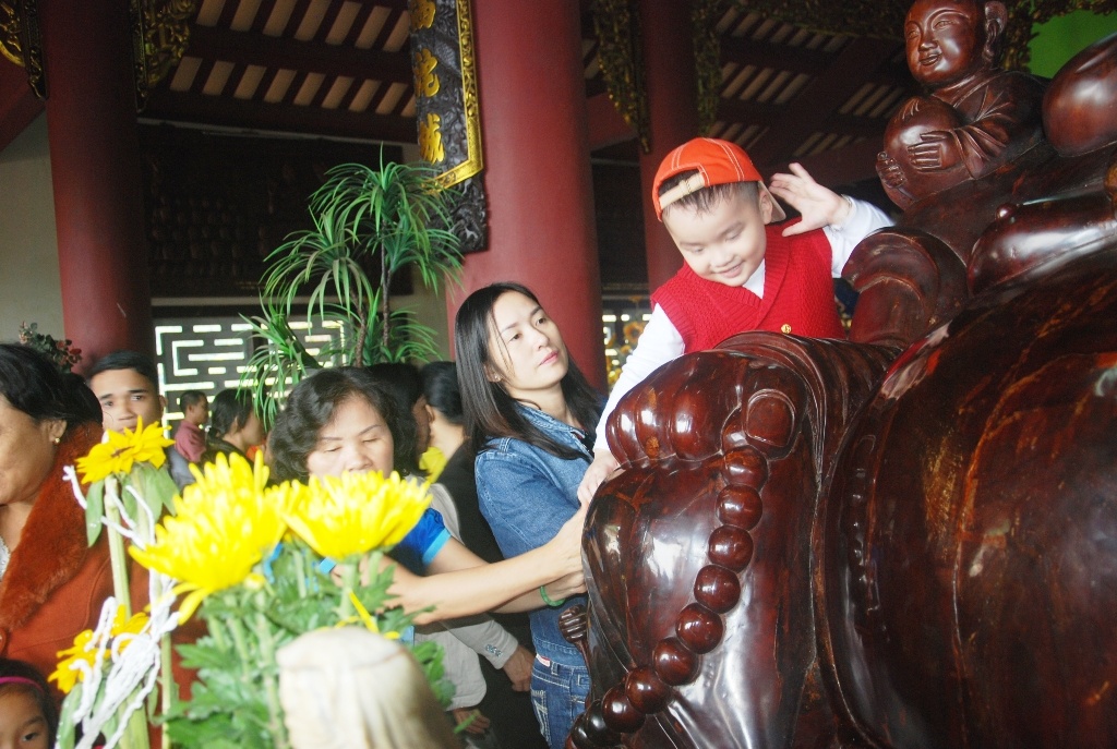 Không những chen lấn, xô đẩy nhau, nhiều người còn bế cả con nhỏ treo lên các bức tượng để sờ vào đầu.