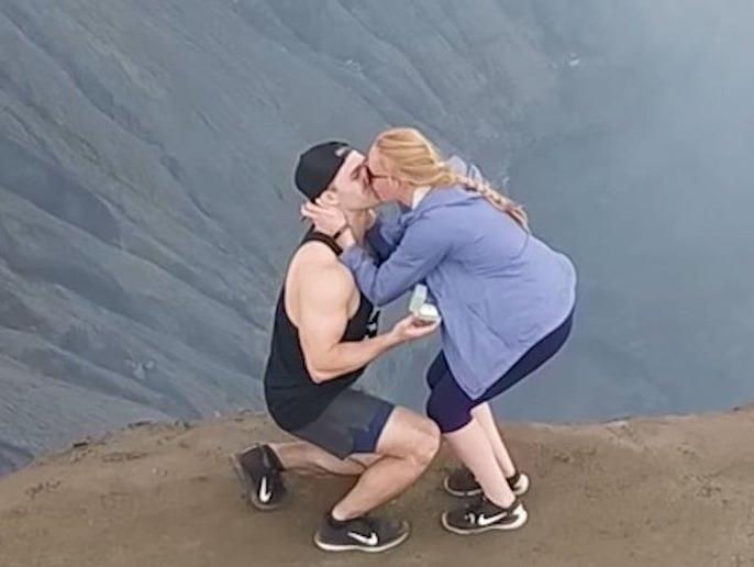 Chang trai cau hon ban gai tren mieng nui lua dang hoat dong hinh anh