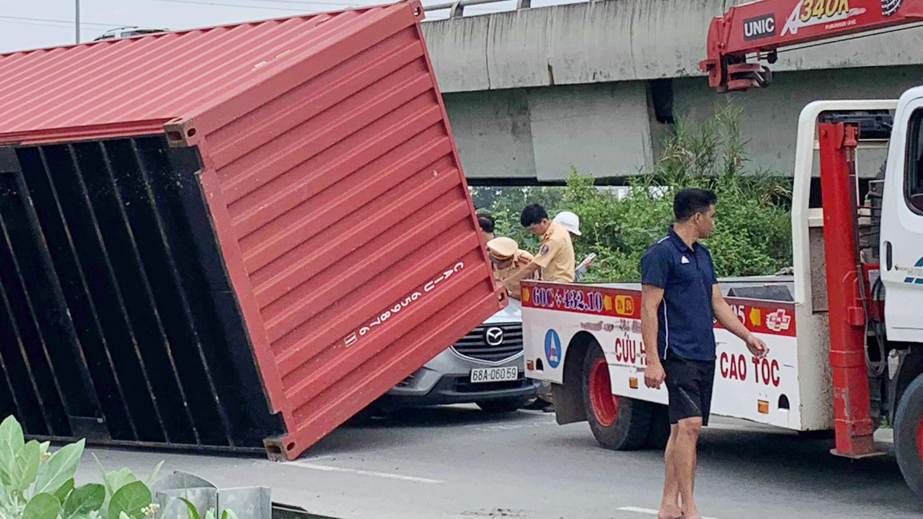 Container lat de oto con, tai xe may man thoat nan hinh anh