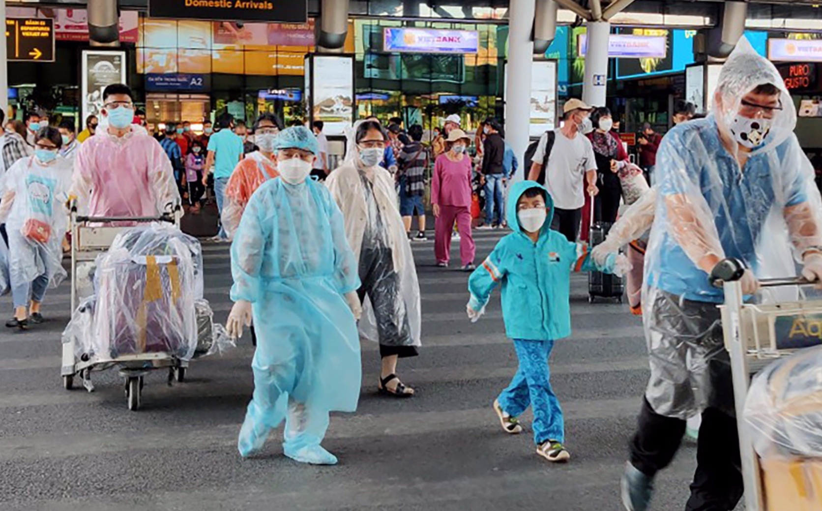 Hanh khach mac ao mua ra san bay Tan Son Nhat phong Covid-19 hinh anh