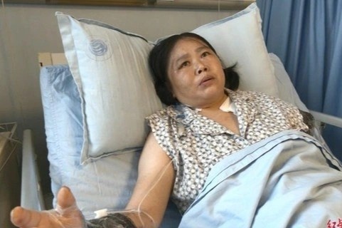 Nguoi phu nu Trung Quoc mat canh tay khi cuu be trai khoi xe tai hinh anh