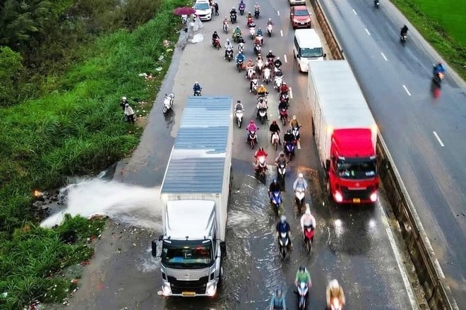 Tai xe dieu khien xe container chan dong nuoc cho xe may qua duong hinh anh