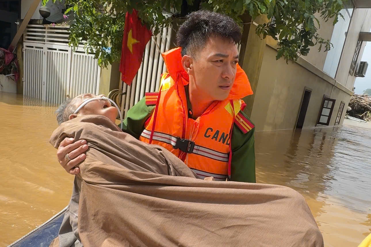 Am long canh chien si cong an om chat cu ba tren duong chay lu hinh anh