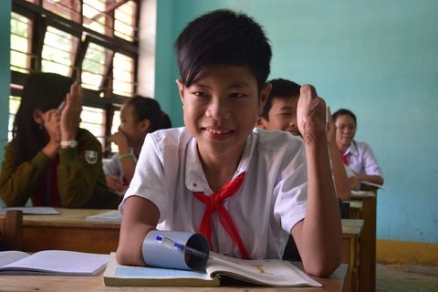 Mat doi ban tay do bom min, cau be dung ong nhua viet bai hinh anh