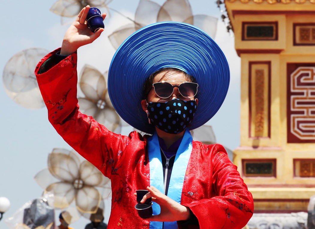 Nguoi mau deo khau trang, kinh den dien ao dai tong duyet trong nang hinh anh