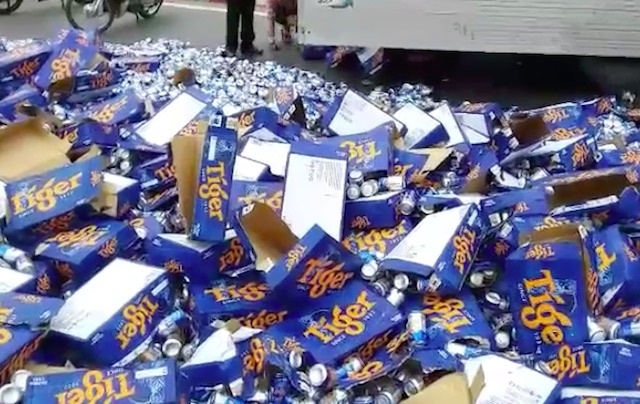 Nguoi dan giup tai xe gom hang tram thung bia do ra quoc lo hinh anh