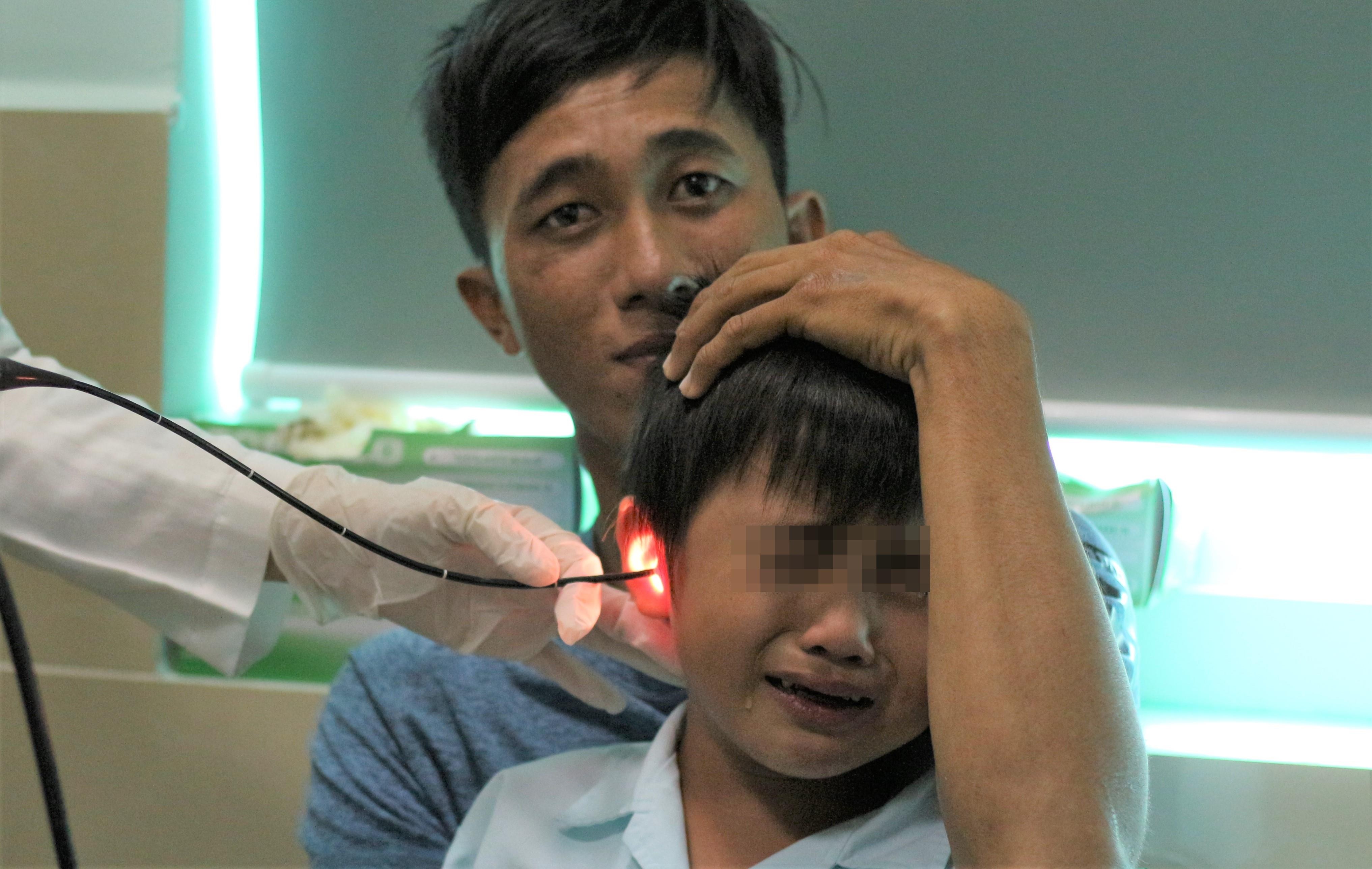 Be 5 tuoi thung mang nhi sau khi nhet pin dien tu vao tai hinh anh